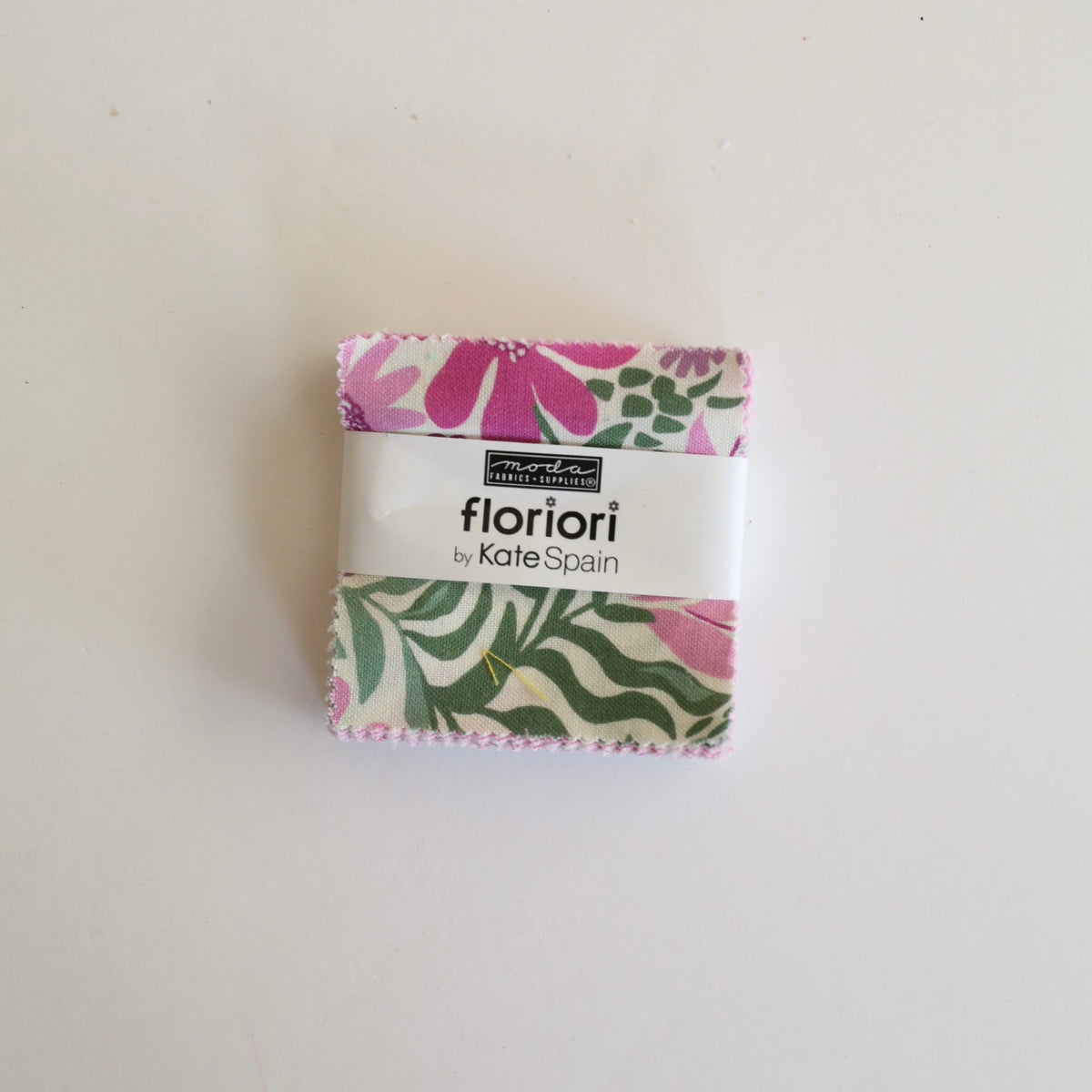A small folded fabric bundle wrapped with a white paper band labeled 'floriori by Kate Spain' on a plain white background.