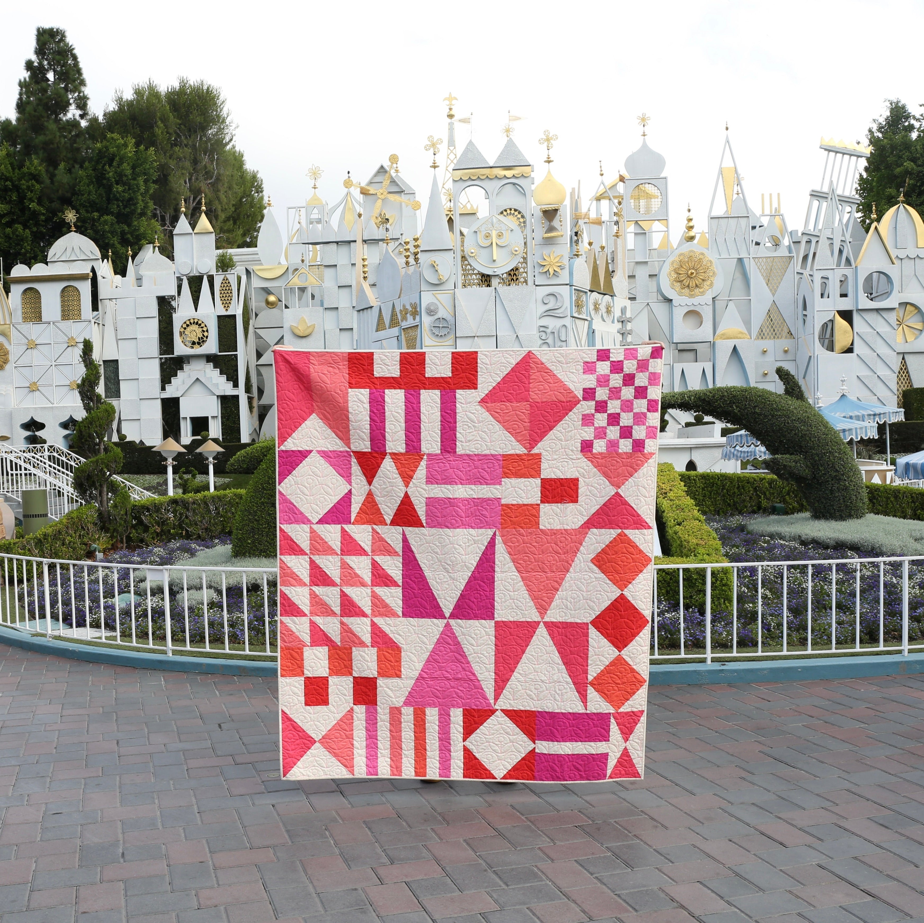 Quilt with geometric pattern in front of a themed park attraction