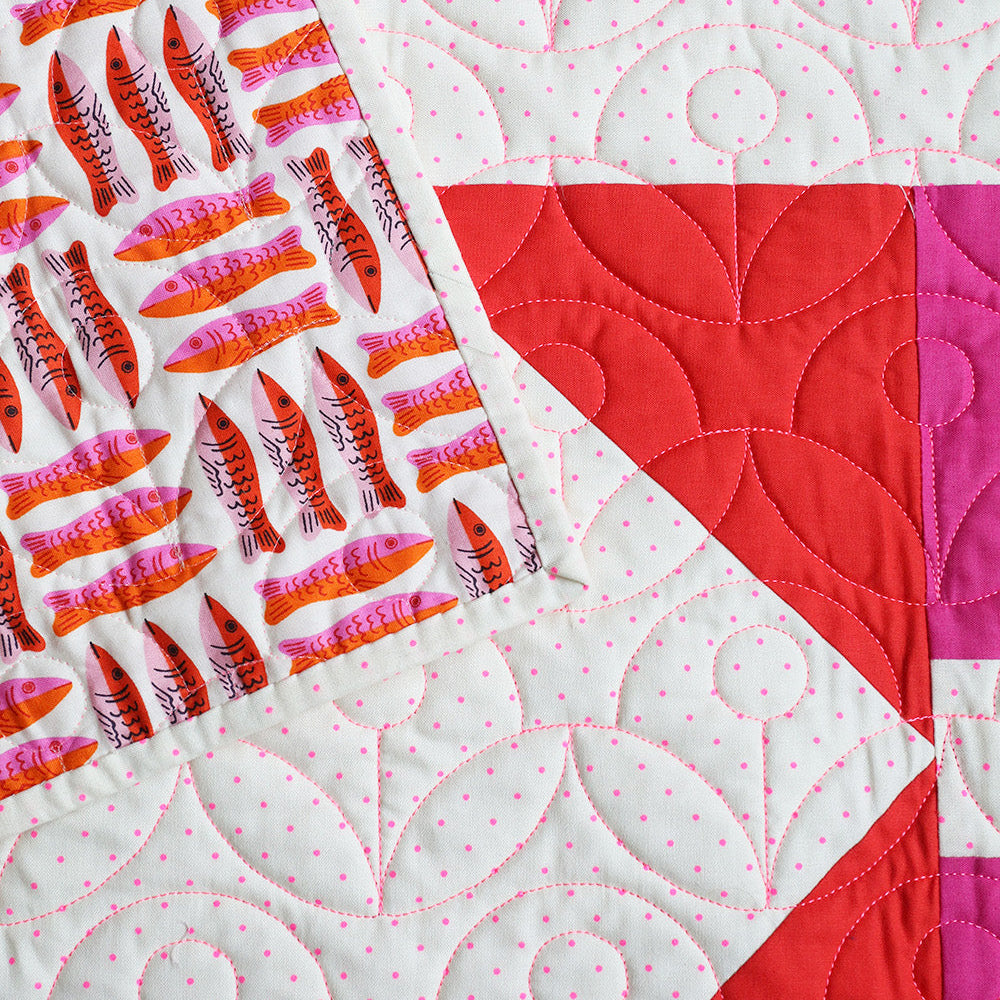 Quilt with colorful patchwork design featuring red, pink, and white patterns.