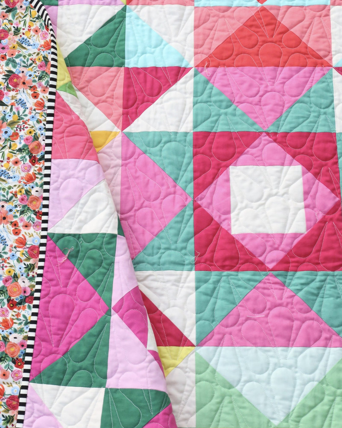 Economy Stars quilt folded back to show the floral backing and striped binding