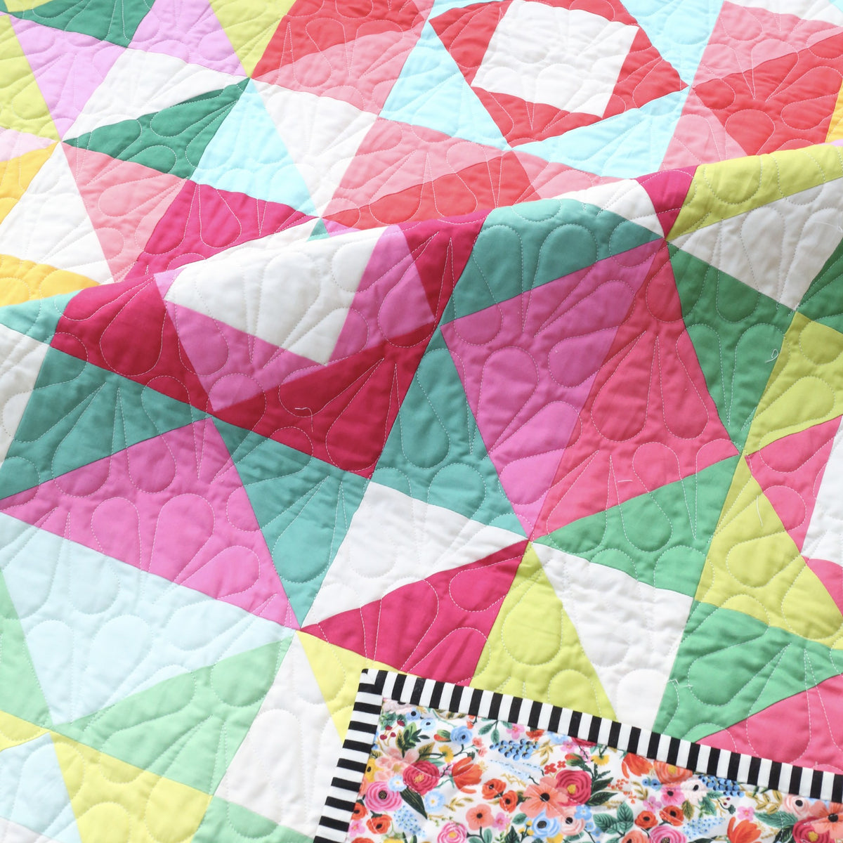 Close-up of Economy Stars quilt blocks with a floral backing and striped binding