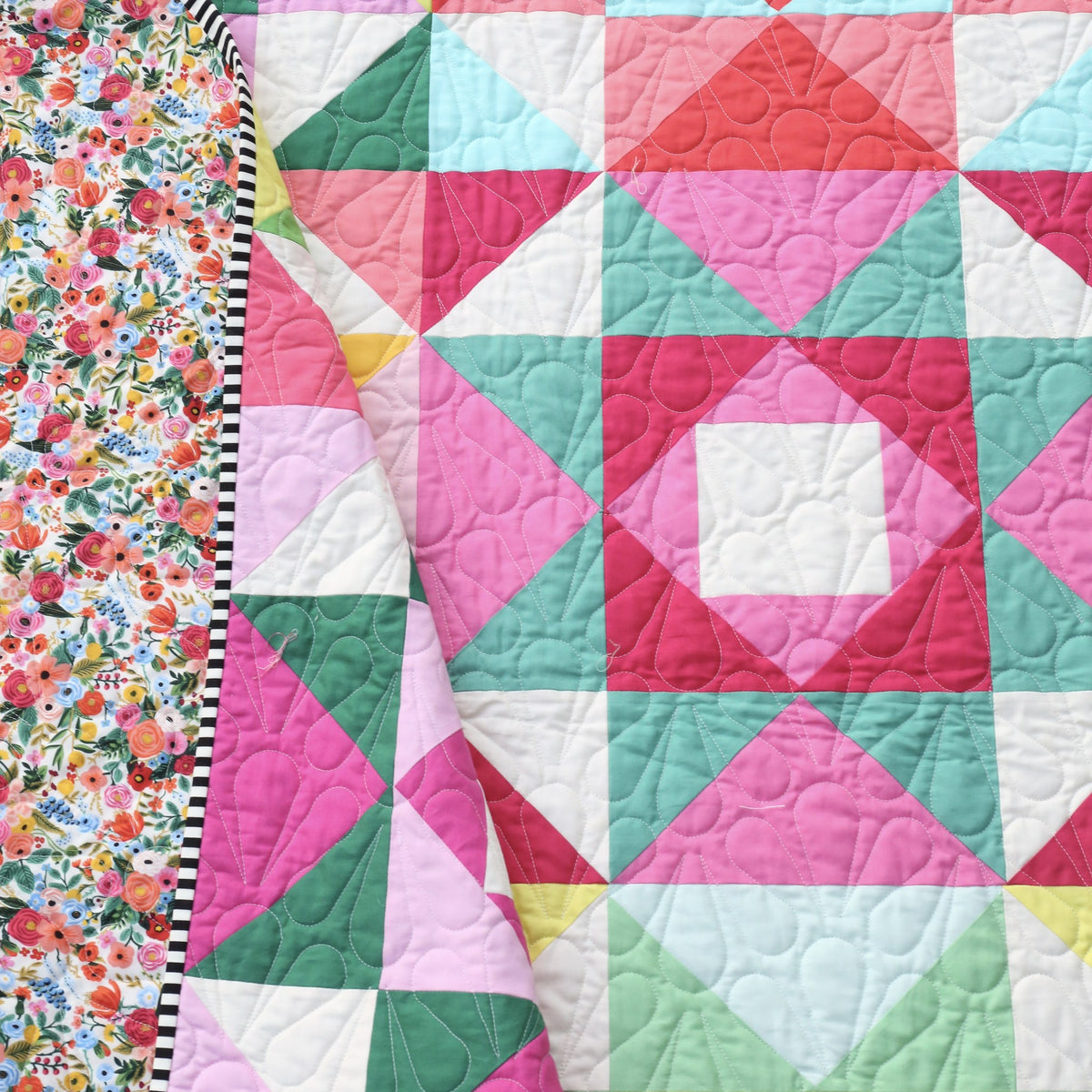 Economy Stars quilt folded back to show the floral backing and black and white striped binding
