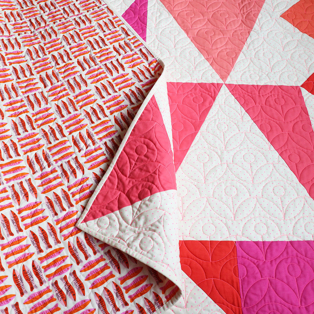 Close-up of a quilt with pink and red geometric patterns