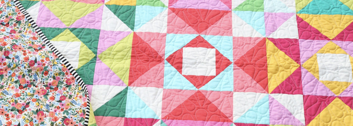 Close-up of the bright Economy Stars quilt with floral backing and striped binding